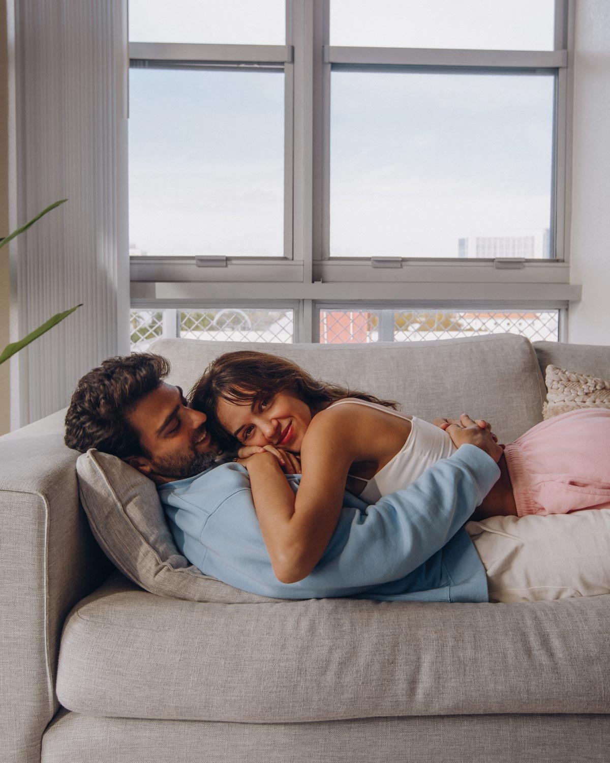 A couple cuddling together on a sofa at home